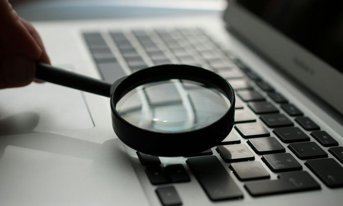 A magnifying glass held over a laptop keyboard
