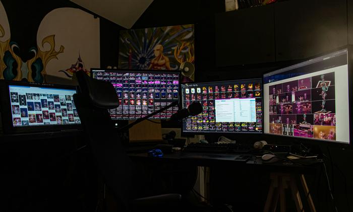 A person sitting in front of three computer monitors