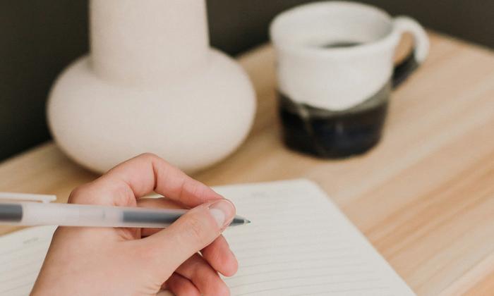 A person writing in a notebook with a pen
